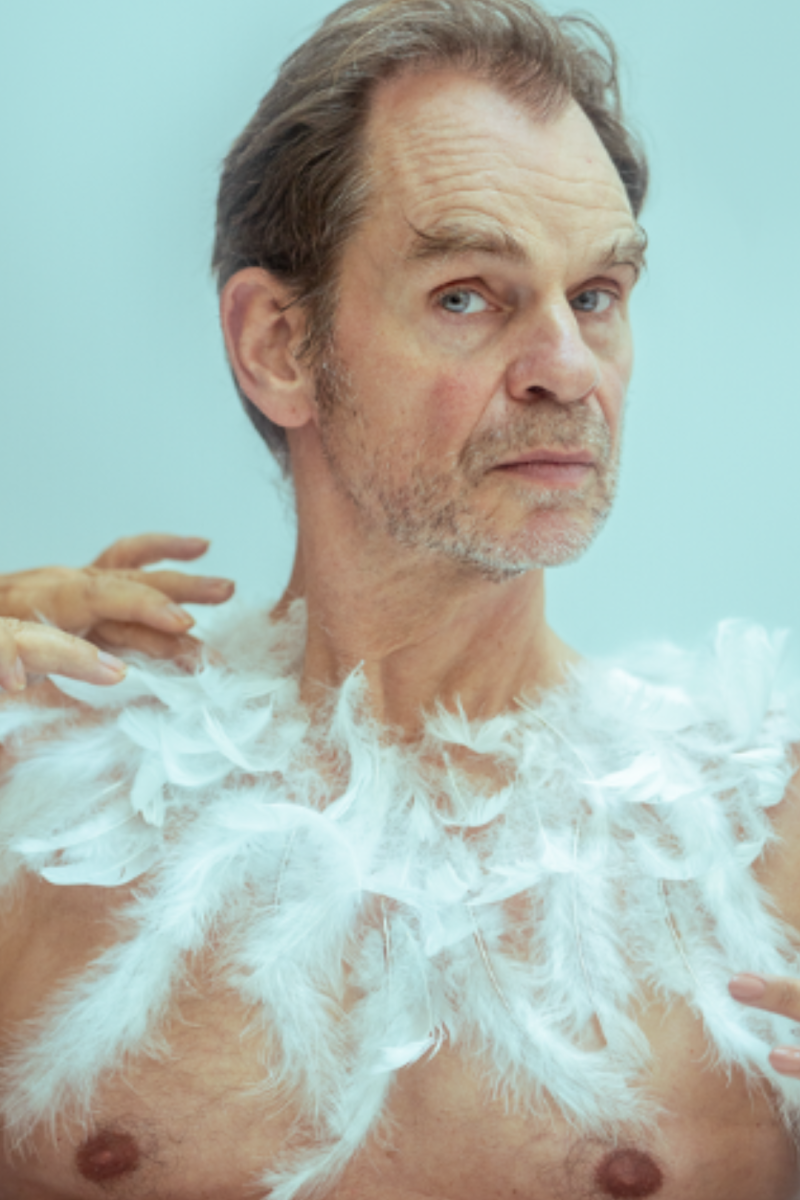Hier is een man te zien met een ontbloot bovenlichaam met veren er op geplakt.