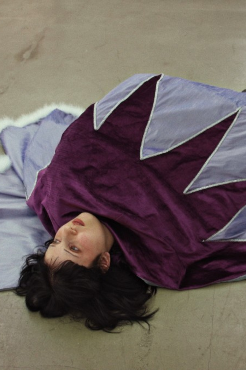 Vrouw ligt op de grond in paars gewaad