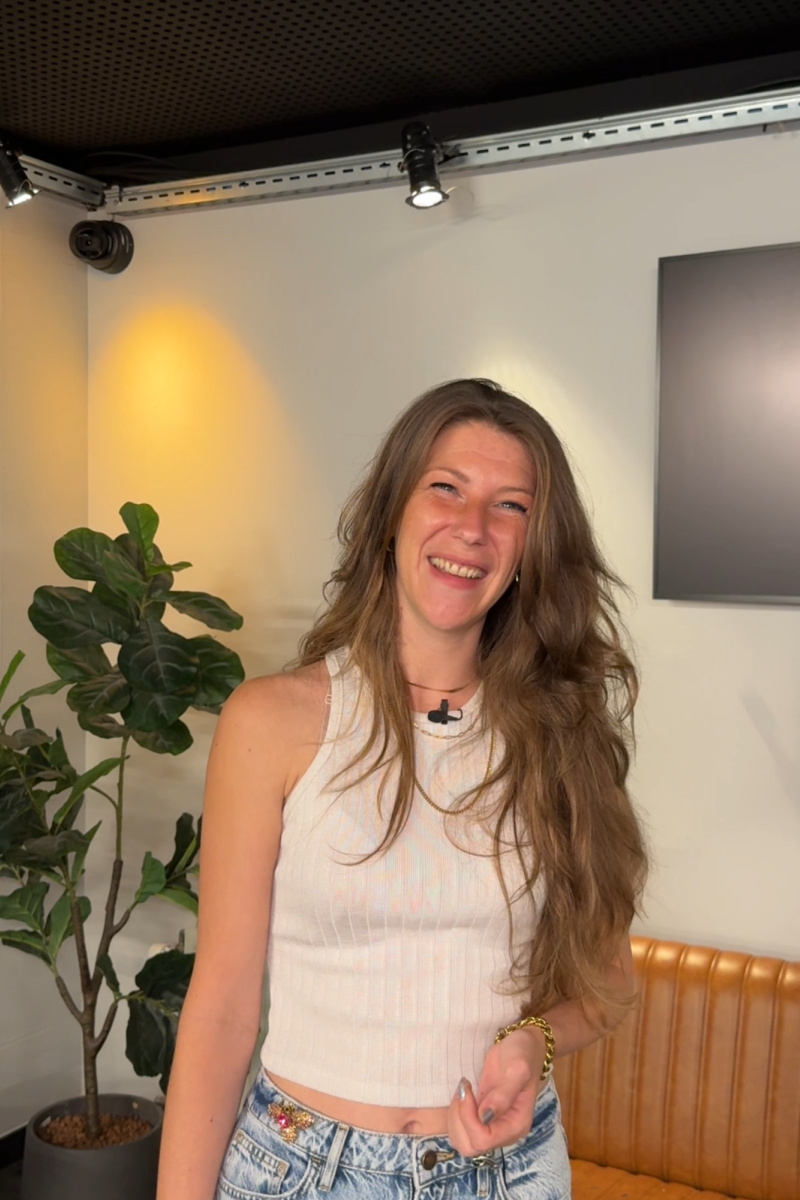 Foto van Nikki, waar dit artikel over gaat. Ze kijkt lachend de camera in. Zee heeft lang haar wat ze los draagt.