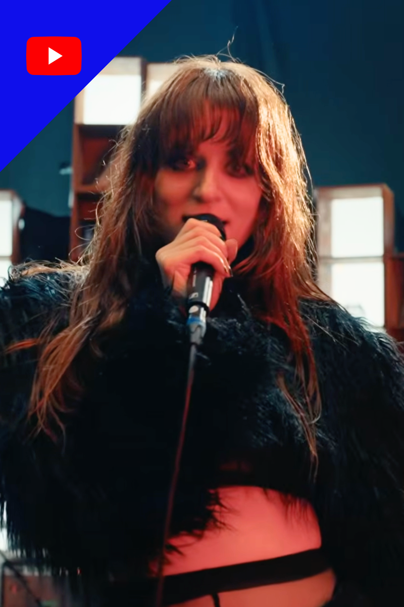 Zangeres MEROL zingt in zwart harige outfit en kijk recht in de camera