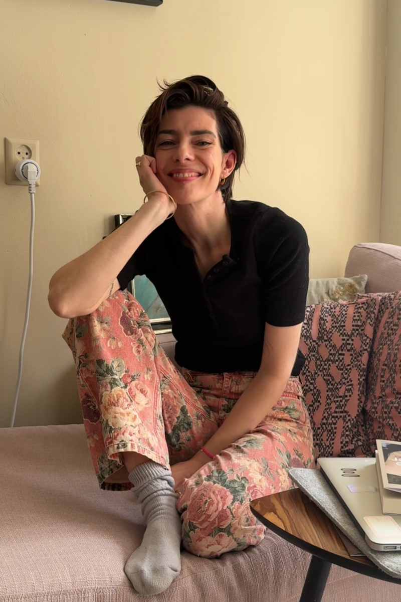 De schrijfster waar dit interview mee is, Sophie Visser, zit op de bank. Ze heeft haar benen opgetrokken en kijkt lachend de camera in.