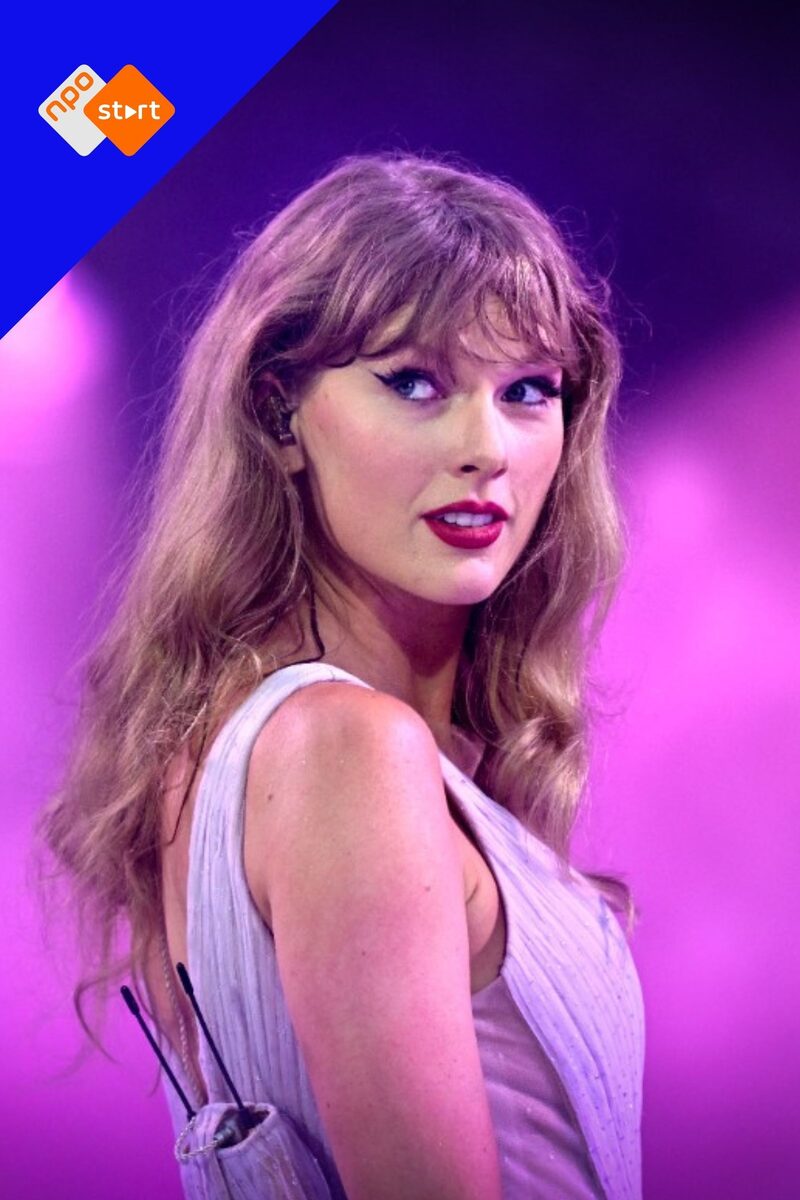Blonde Amerikaanse zangeres Taylor Swift kijkt zwoel naar de camera met roze licht achter haar.