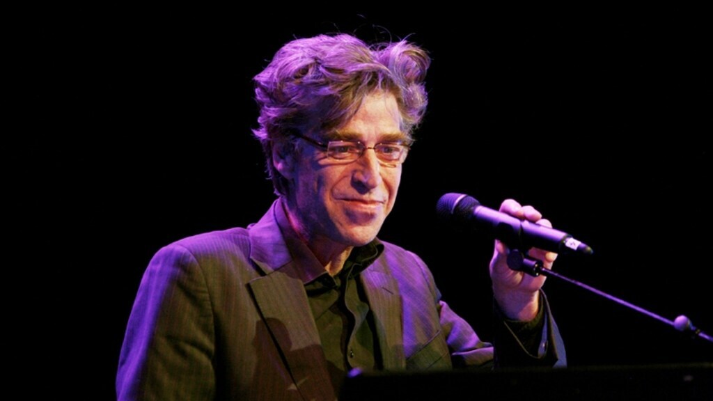 Maarten van Roozendaal verstelt zijn microfoon met een lach op zijn gezicht