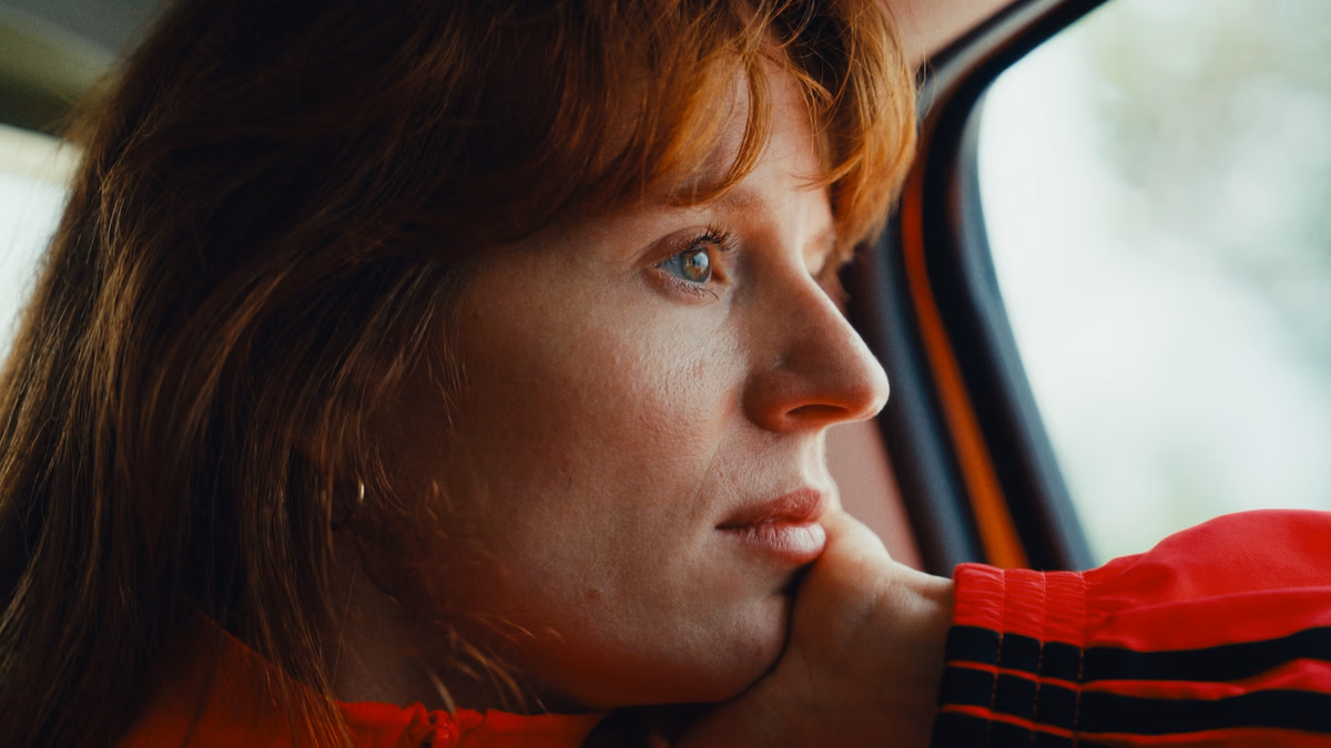 MEROL zit in een auto en kijkt uit het raam