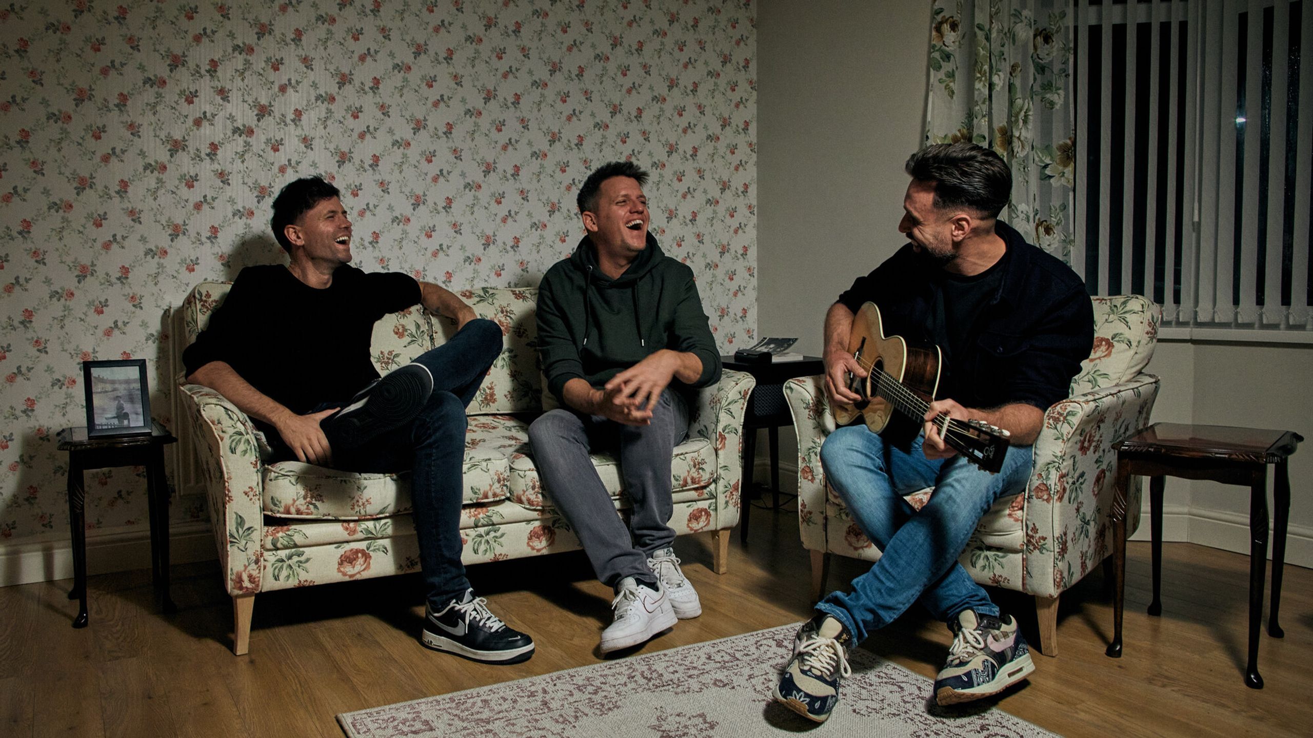 Nick Schilder, Simon Keizer en Kees Tol zitten in George Harrison's oude huis. Het interieur is vol van bloemen.