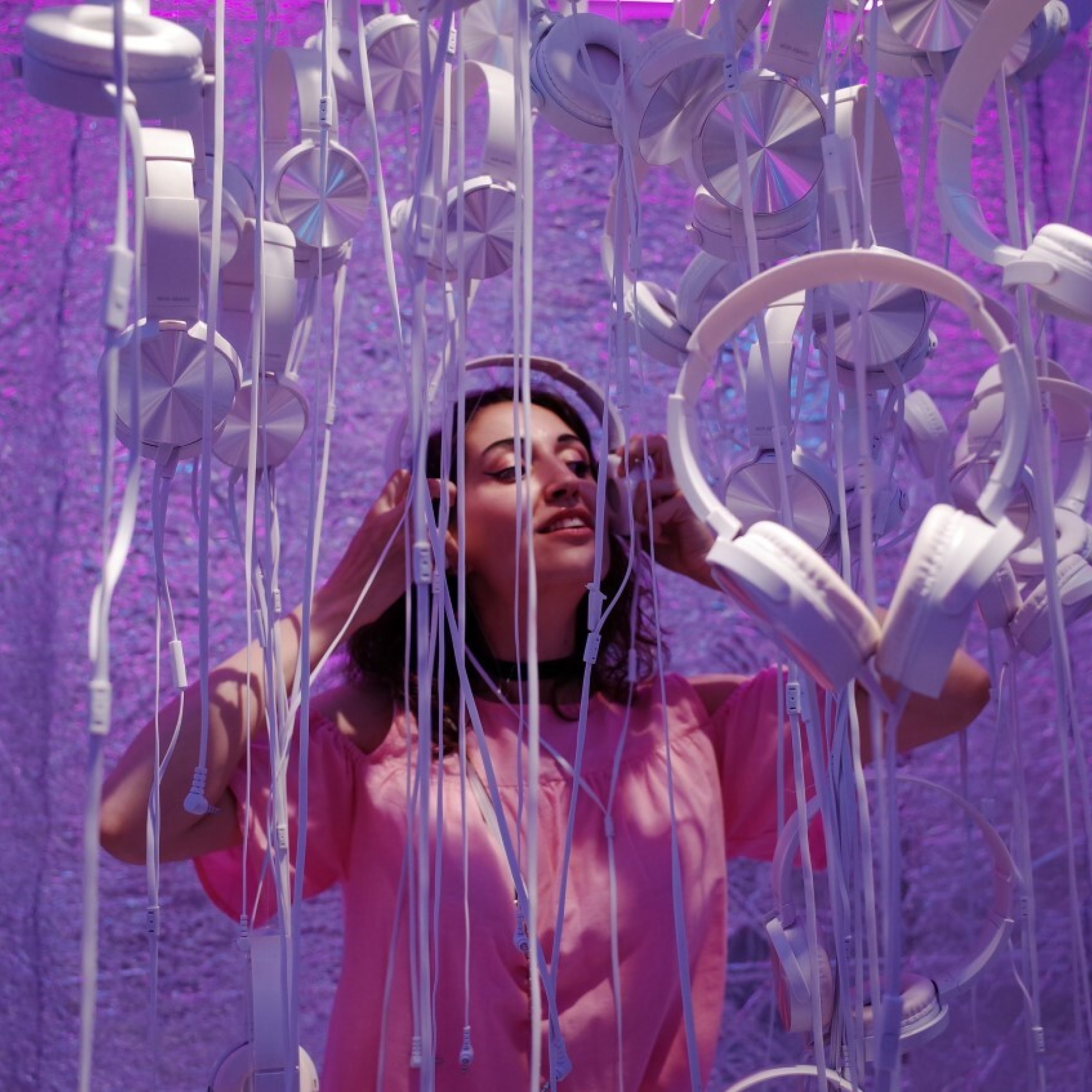 Vrouw met koptelefoon tussen slingers van andere koptelefoons