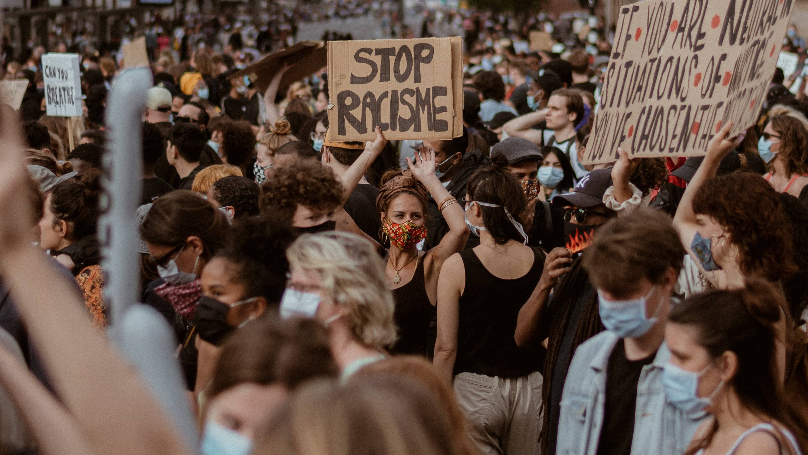 Vrouw houdt een bord omhoog tijdens demo waarop staat: Stop racisme